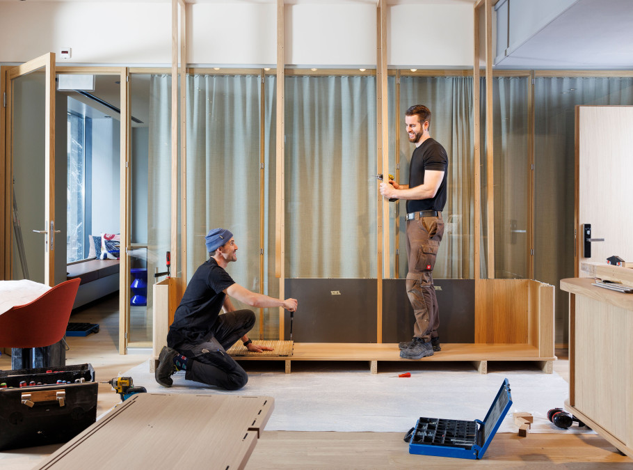 Zwei Männer arbeiten an einem Regal aus Holz in einer Hotellobby