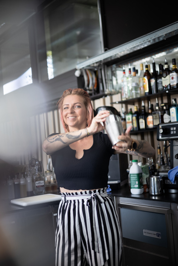 Junge Frau mit pinken Haaren shaket einen Cocktail