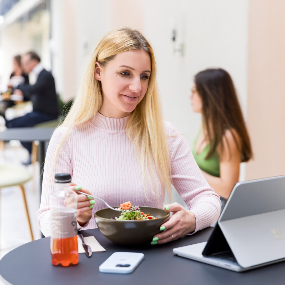 Frau sitzt vor einem Laptop und isst