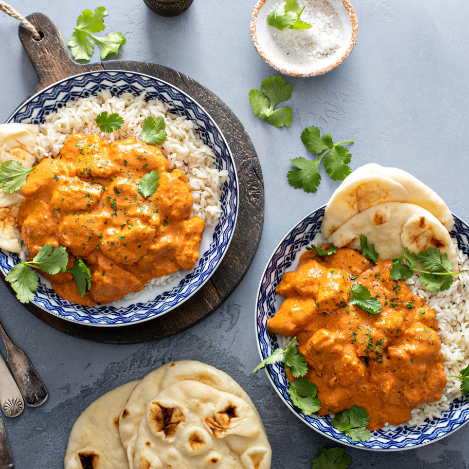 Tikka Masala mit Poulet in Tellern, darum herum frische Zutaten