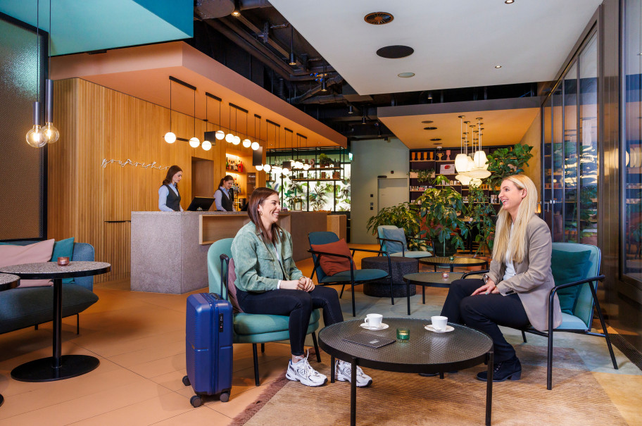 Hotellobby mit zwei Frauen, die zusammen an einem Tisch sitzen