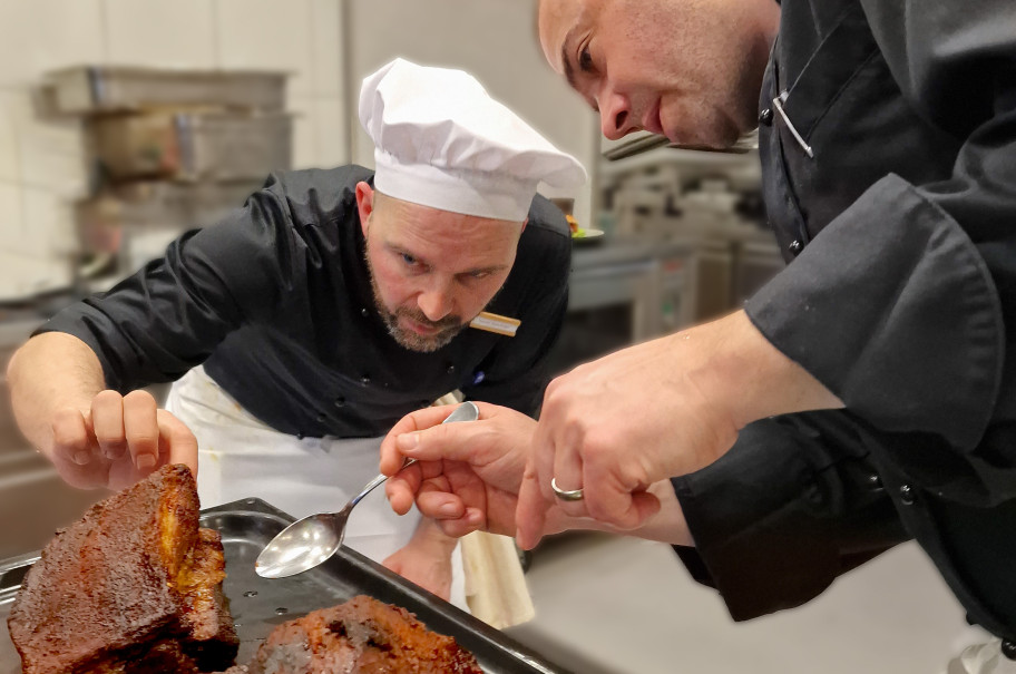 Zwei Köche schneiden ein grosses Stück Fleisch