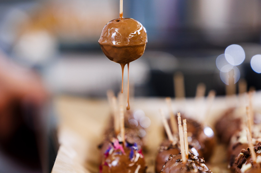 Hand hält Cakepop von der Schokoladenglasur fliesst