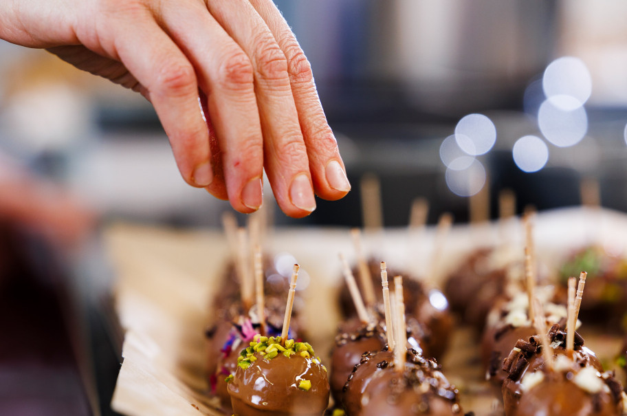 Hand hält Cakepop von der Schokoladenglasur fliesst