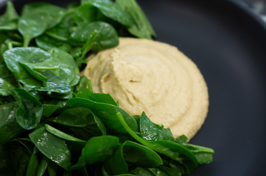 Schüssel mit Hummus und Spinatsalat