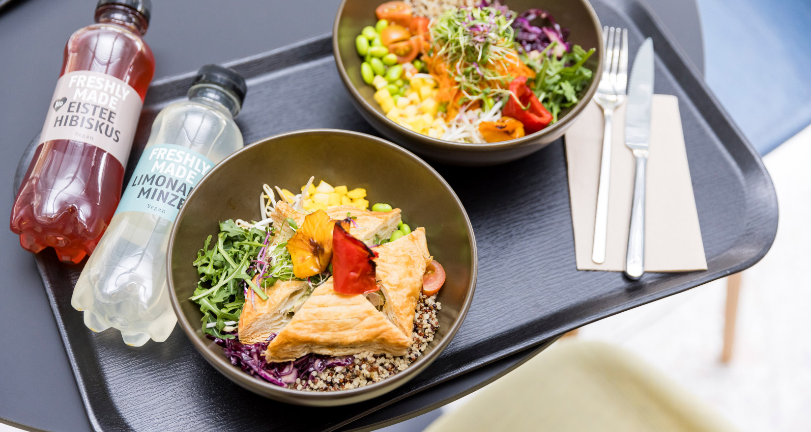 Zwei Bowls mit frischem Lunch auf einem Plateu mit Getränken