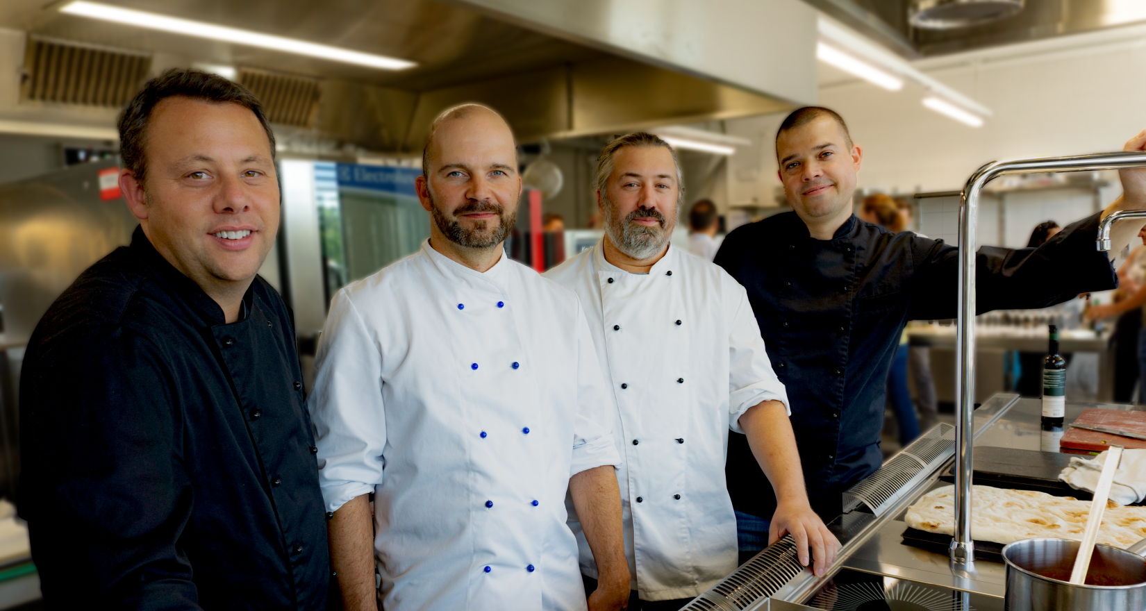 Vier Köche in Uniform in einer Gastronomieküche