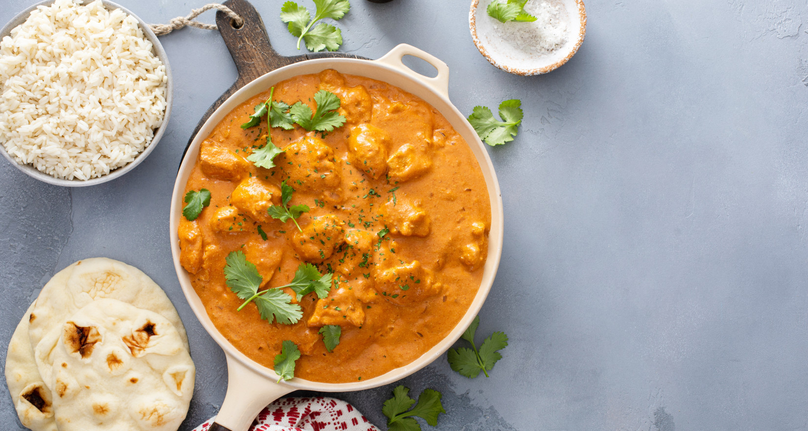 Tikka Masala mit Poulet in einer Pfanne, darum herum frische Zutaten