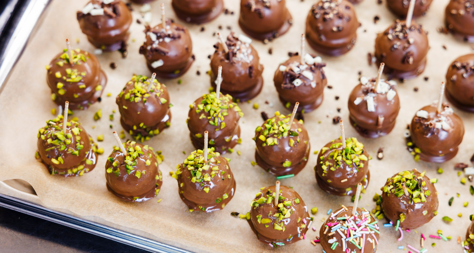 Cakepops mit Schokoladenglasur und Streuseln auf einem Blech