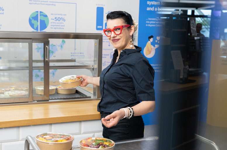 Frau stellt einen Salat in eine Vitrine