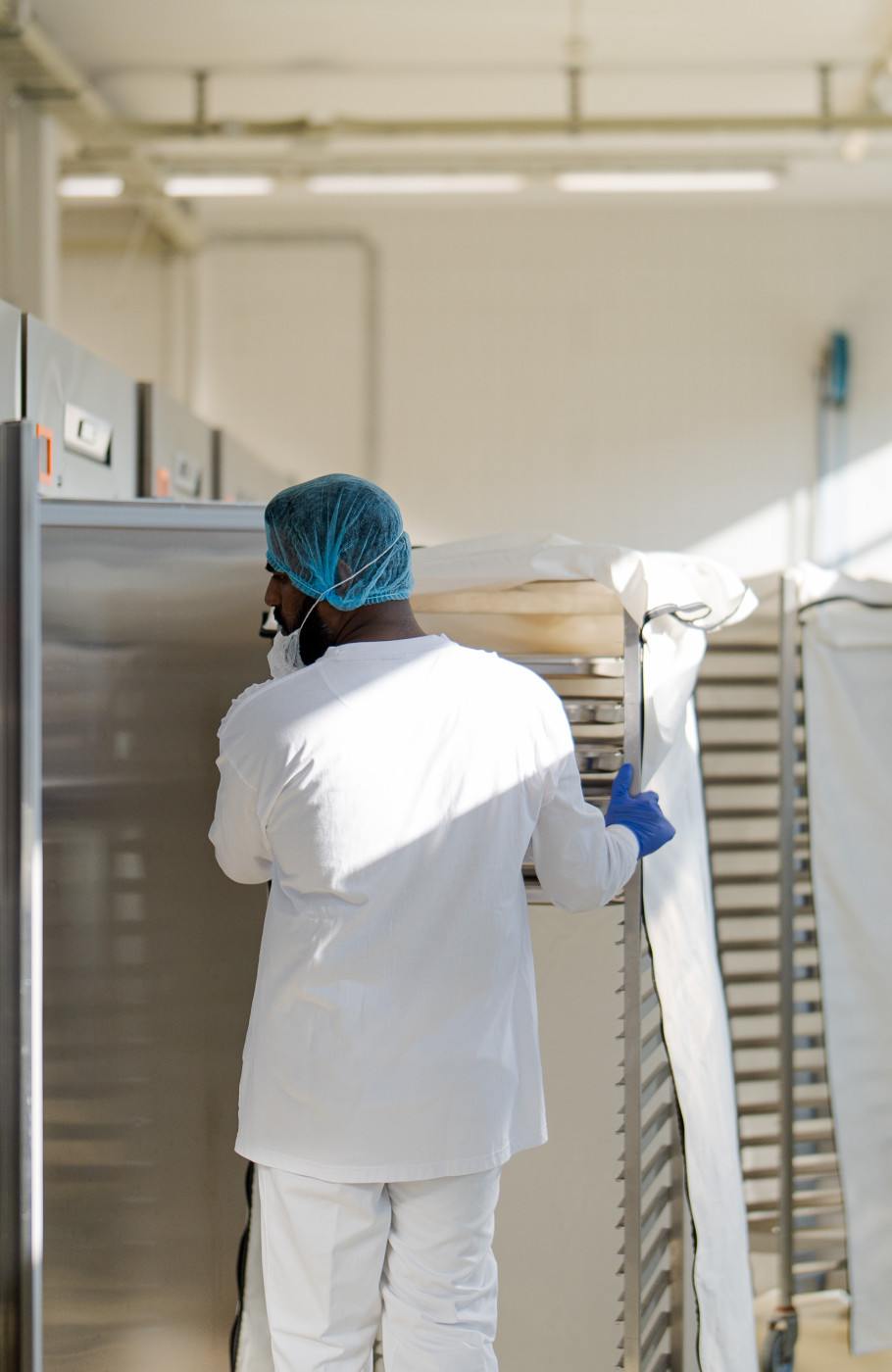 Person mit Schutzanzug und Haube in einer Produktion