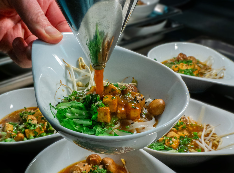 Schüssel mit Einlagen wird mit Suppe gefüllt