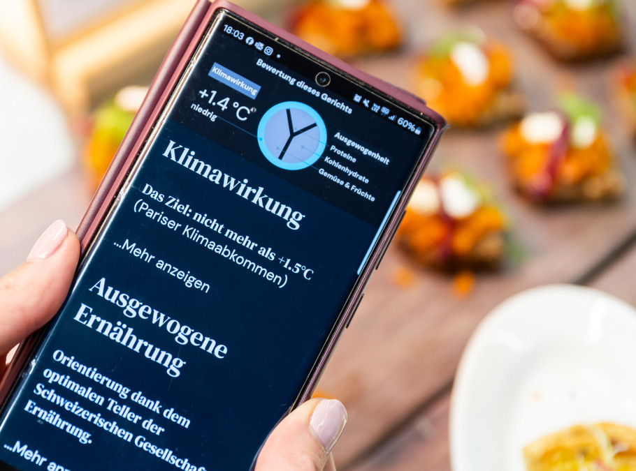 Handy zeigt Daten zur Klimaerwärmung, dahinter Häppchen