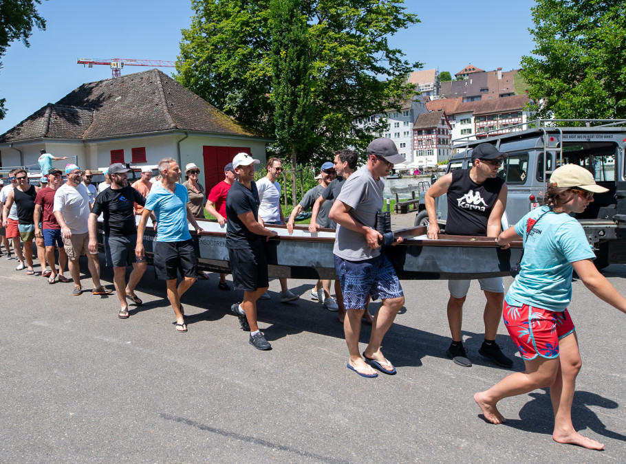 Menschen tragen in einer Gruppe ein Drachenboot zum See