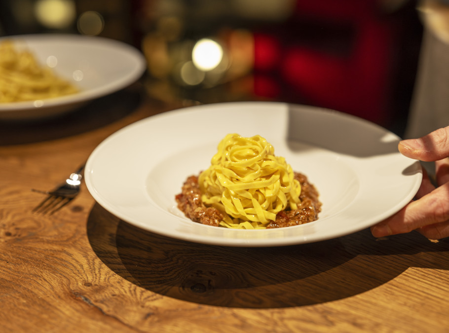 Teller mit Tagliatelle und einer Edelpilzbolognese auf einem Tisch