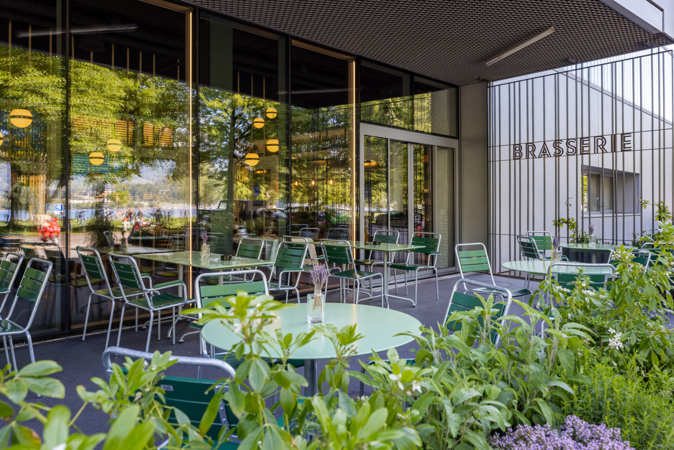 Begrünte Terrasse mit Fensterfront und Bistrotischen