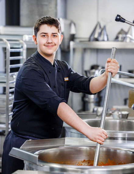 Jungkoch in Kochjacke in einer Gastronomieküche