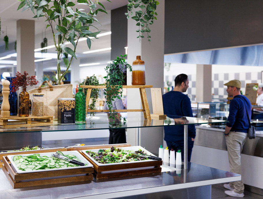 Zwei Männer hinter einem Buffet mit frischem Salat an der Essensausgabe